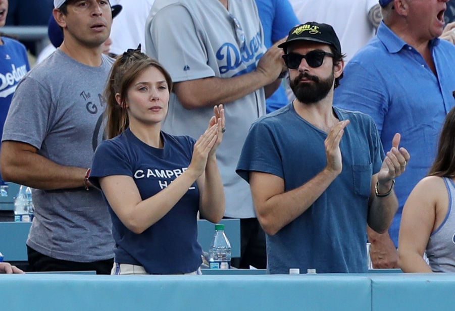 Elizabeth Olsen at a Dodgers game with boyfriend Robbie Arnett. An emerald ring is just visible on her left ring finger.