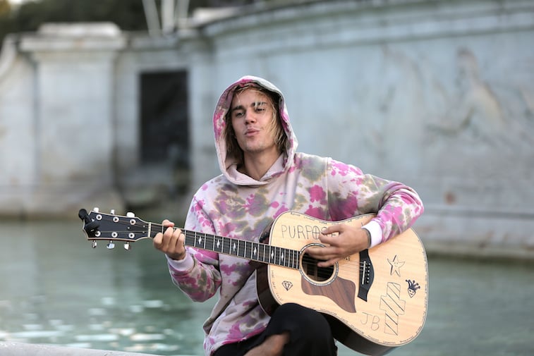 Justin Bieber playing guitar at the Buckingham Palace fountain.
