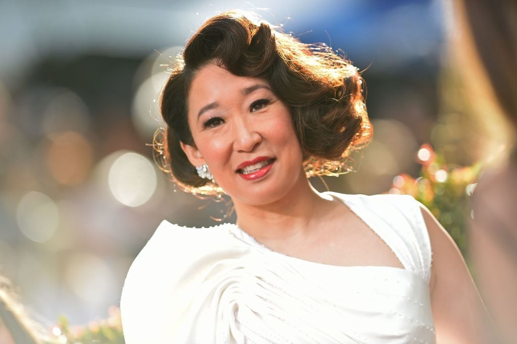 Sandra Oh smiles wearing a white gown at the Golden Globes