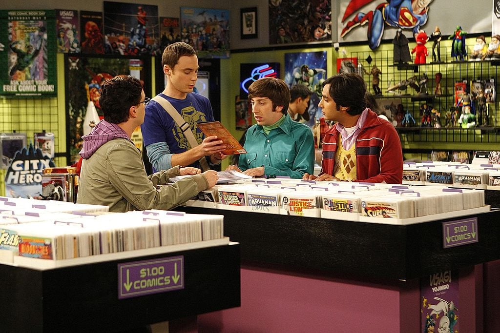 Leonard (Johnny Galecki, far left) and Raj (Kunal Nayyar, far right) look on as Sheldon (Jim Parsons, second from left) and Howard (Simon Helberg, second from right) stake their best comic books on a bet to determine the species of a cricket