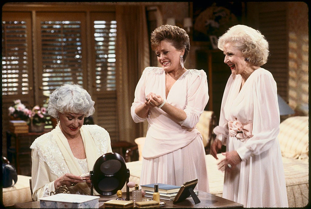 Bea Arthur, Rue McClanahan and Betty White wearing white dresses and smiling