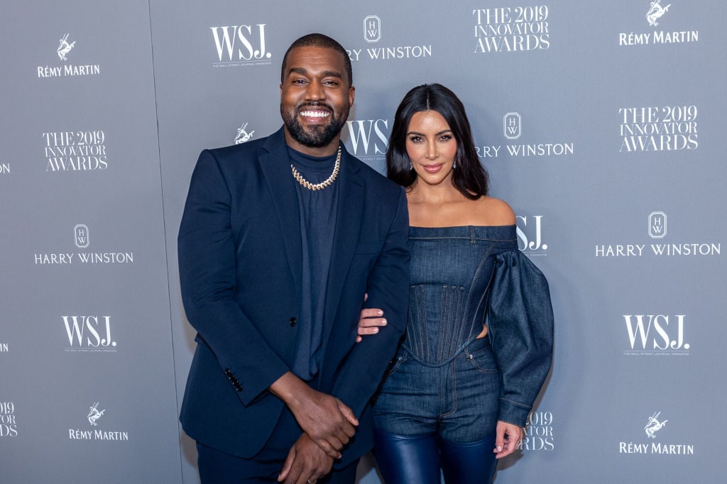 Kanye West and Kim Kardashian West pose together at an event in matching navy blue outfits.
