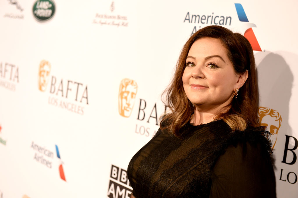 Melissa McCarthy wearing black in front of a repeating background