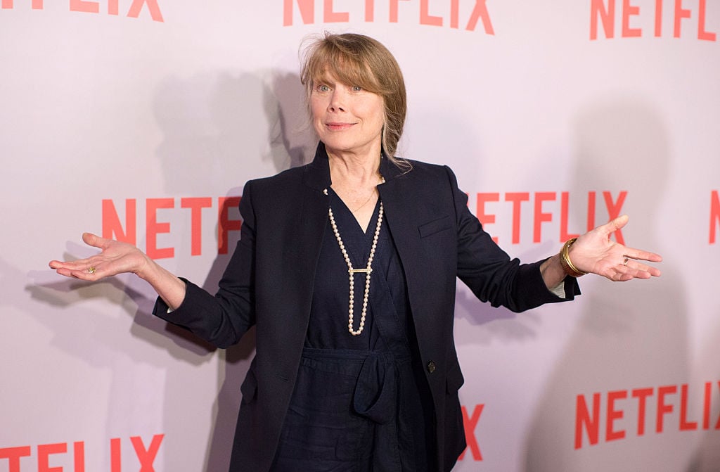 Sissy Spacek shrugging in front of Netflix backdrop.