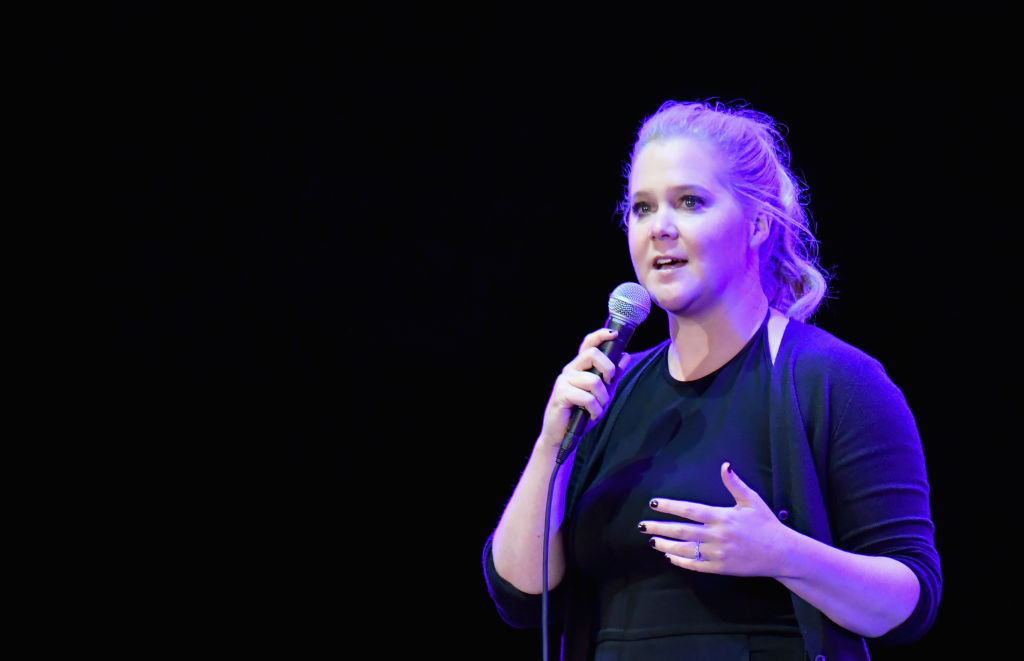 Amy Schumer on stage holding a microphone