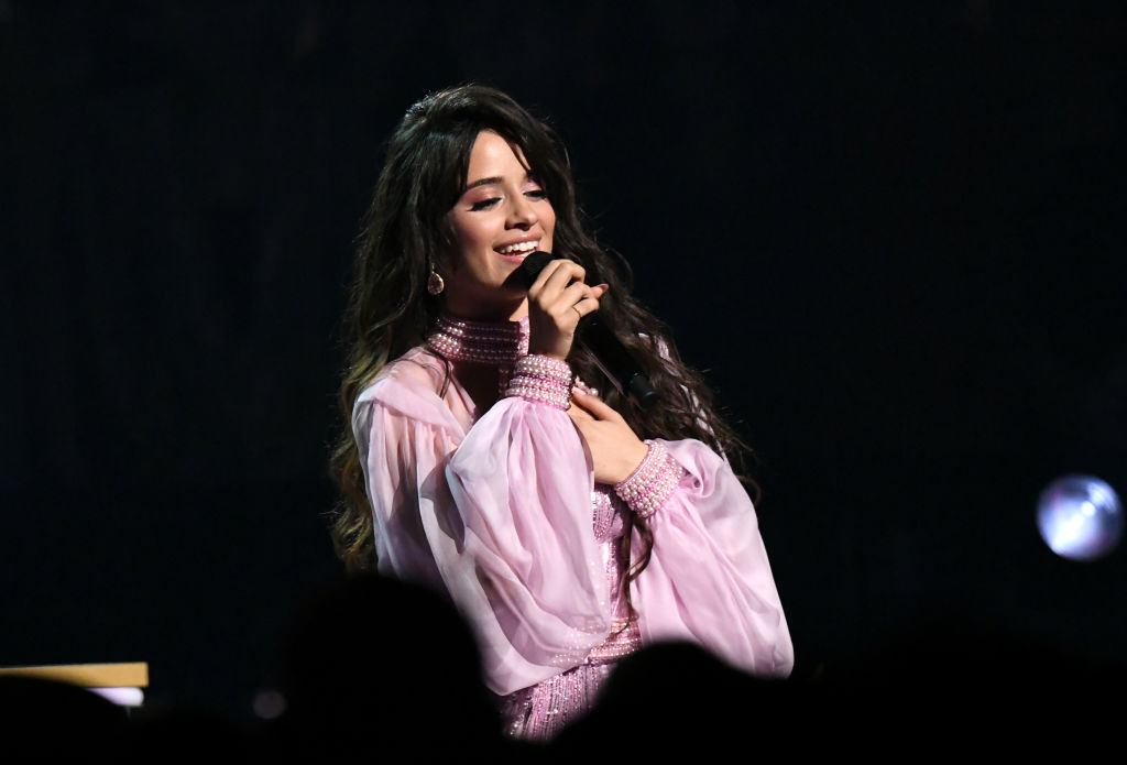 Camila Cabello wearing pink holding a microphone