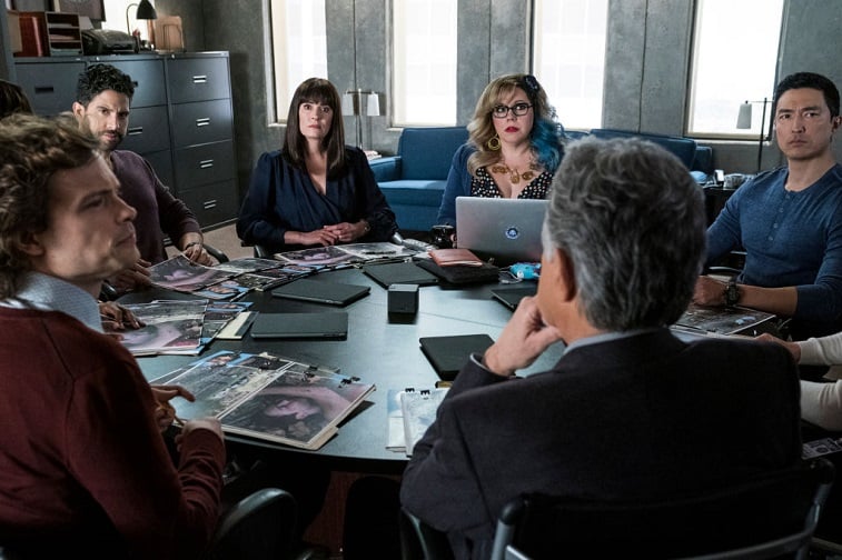 Cast members sit around a table while filming for Criminal Minds season 15.