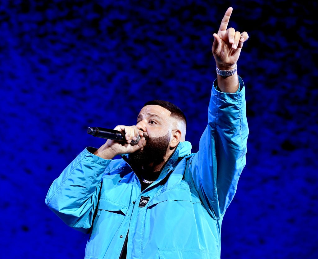 DJ Khaled holding a microphone, wearing a blue jacket