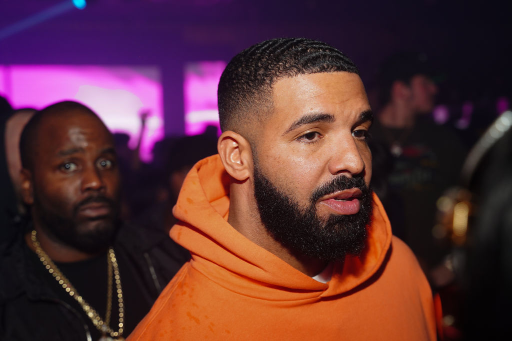 Drake in an orange hoodie looking off camera