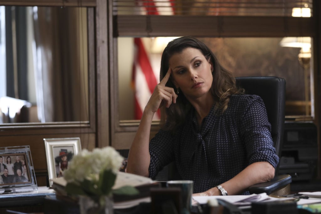 Bridget Moynahan as Erin Reagan on set of 'Blue Bloods' sitting at a desk with her head resting on her hand