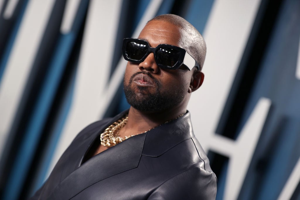Kanye West wearing sunglasses and a leather jacket, looking off camera