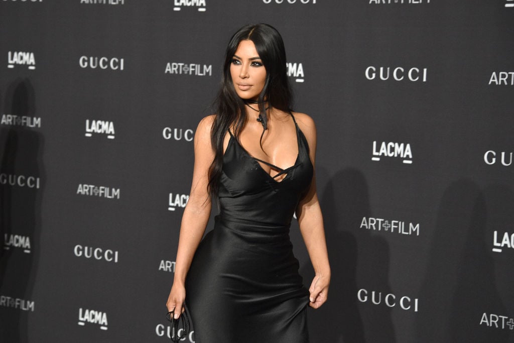 Kim Kardashian in black in front of a repeating background