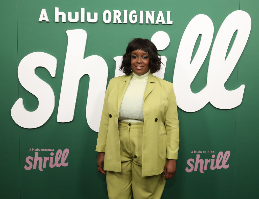 Lolly Adefope wearing green in front of a 'Shrill' promo backdrop