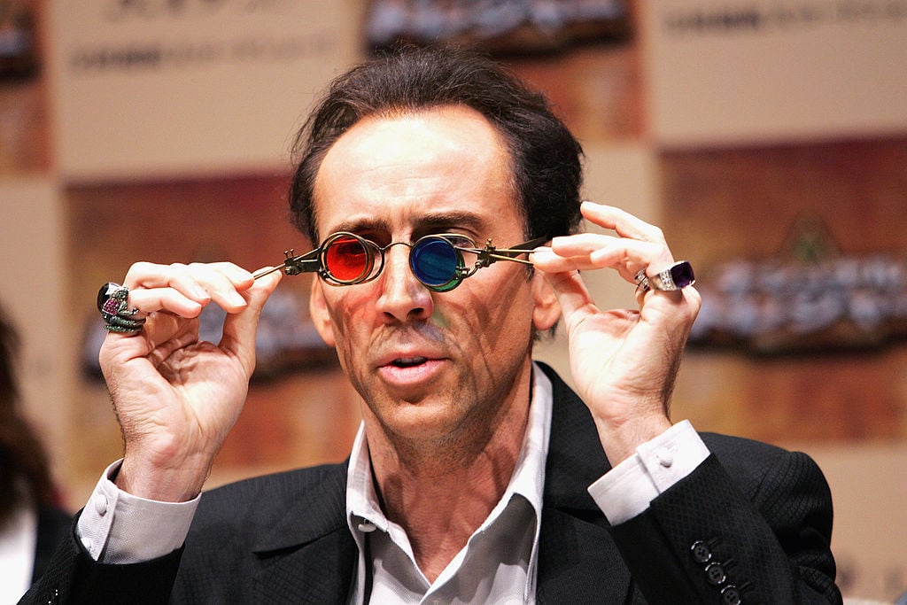 Nicolas Cage holding coloured prop glasses from 'National Treasure' to his face during a press conference