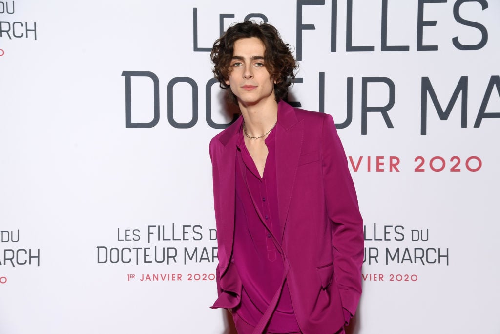 Timothée Chalamet wearing bright pink in front of a repeating background