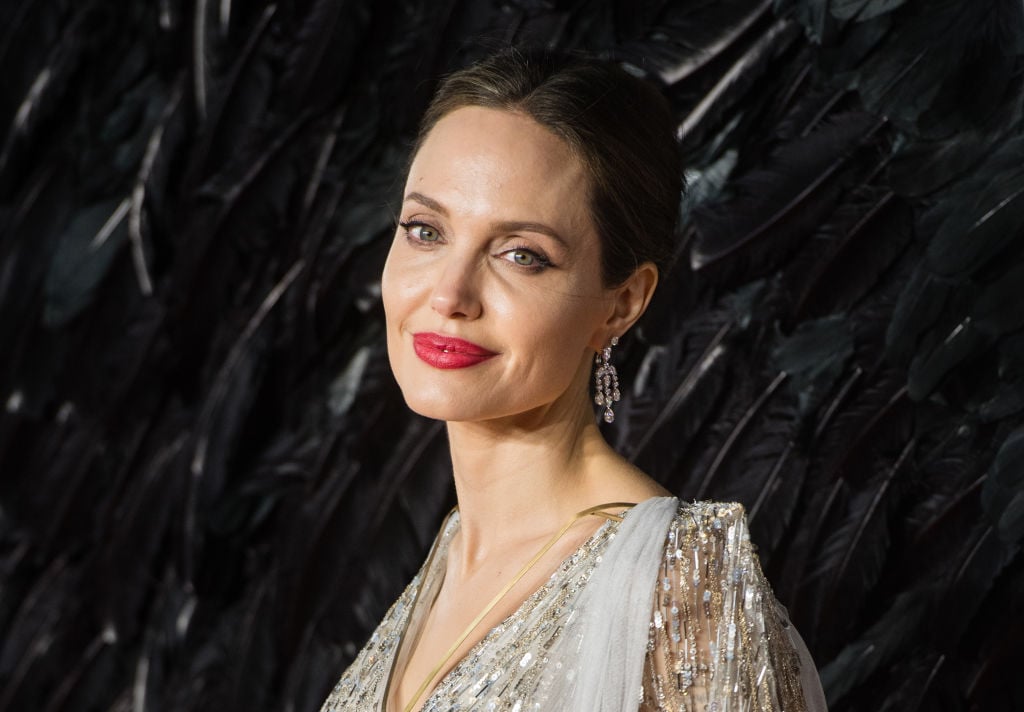 Angelina Jolie smiling in front of a textured background