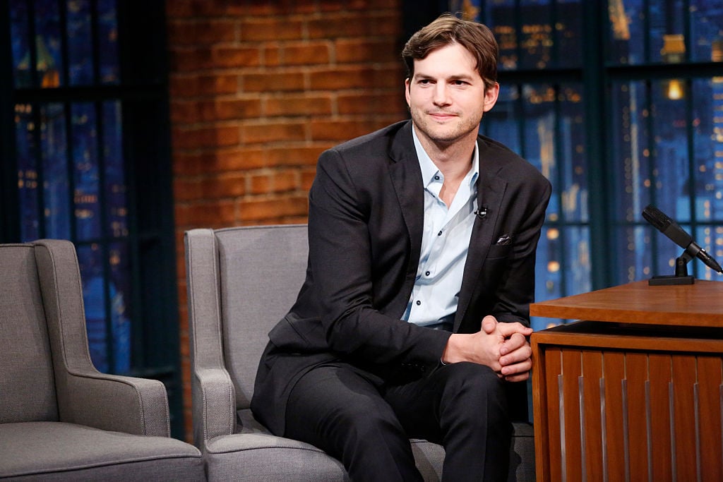 Ashton Kutcher smiling on a couch
