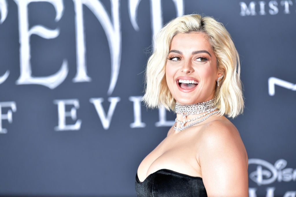 Bebe Rexha smiling in front of a repeating background