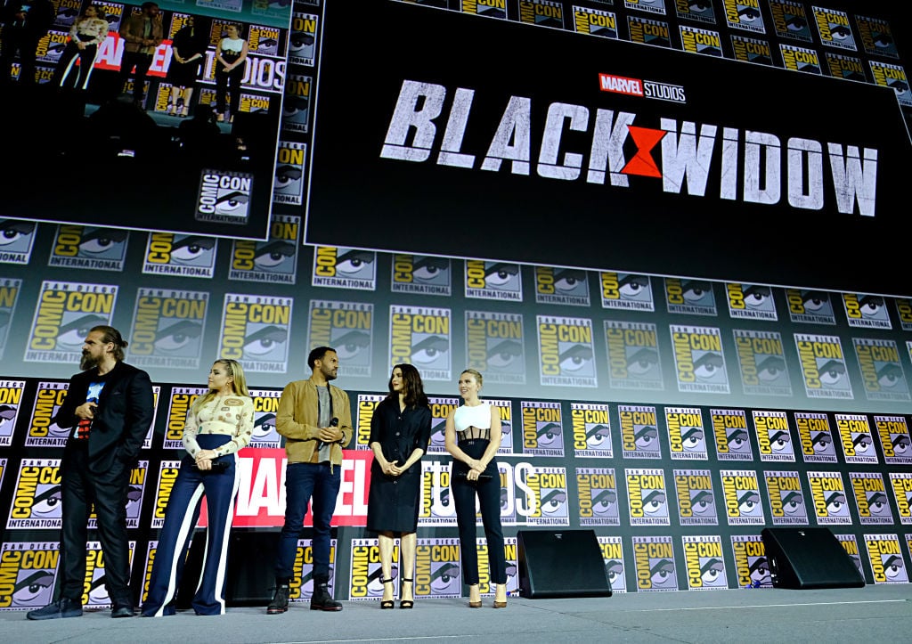 Cast of 'Black Widow' on stage with repeating background