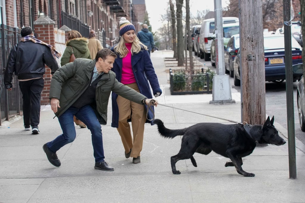 Jamie Reagan (Will Estes) and Eddie Janko (Vanessa Ray) walking a black dog