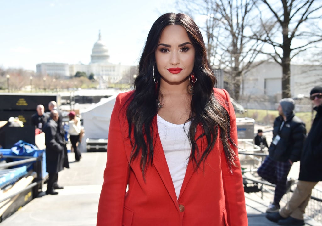 Demi Lovato smiling in a red blazer