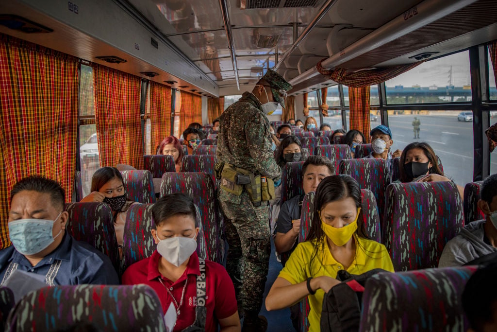 A Filipino policeman inspects a bus at a checkpoint as authorities begin implementing lockdown measures on March 16, 2020