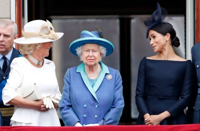 Camilla, Duchess of Cornwall and Meghan, Duchess of Sussex stand behind Queen Elizabeth II as they watch a flypast to mark the centenary of the Royal Air Force on July 10, 2018