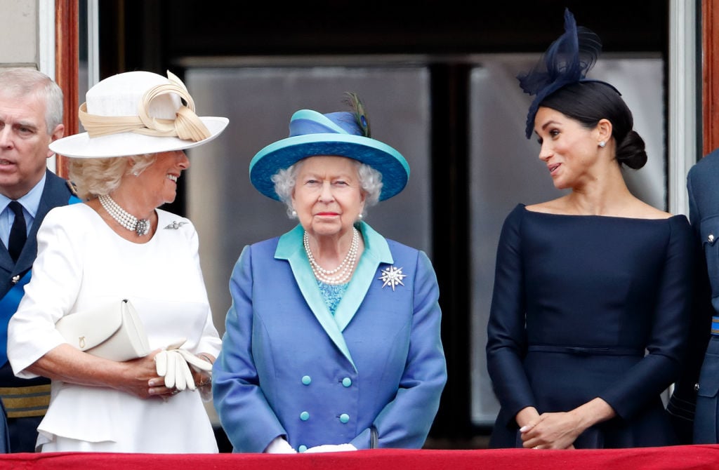 Camilla, Duchess of Cornwall and Meghan, Duchess of Sussex stand behind Queen Elizabeth II as they watch a flypast to mark the centenary of the Royal Air Force on July 10, 2018