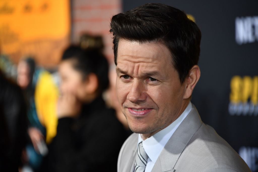 Mark Wahlberg in a white suit jacket looking away from the camera