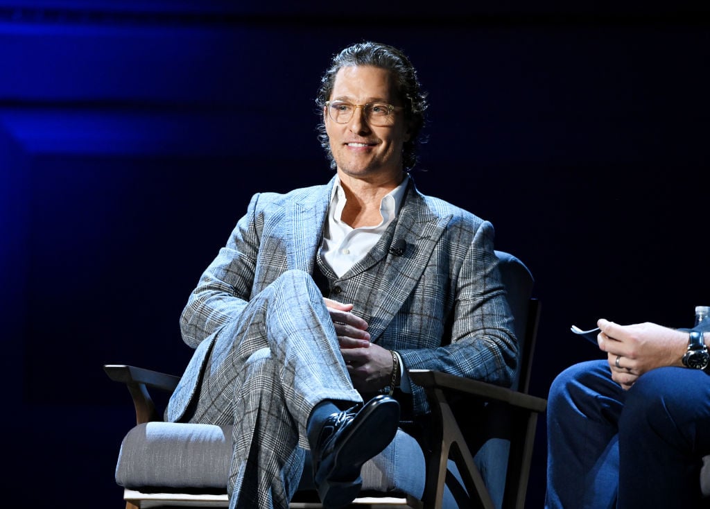 Matthew McConaughey in a plaid suit sitting on a stage