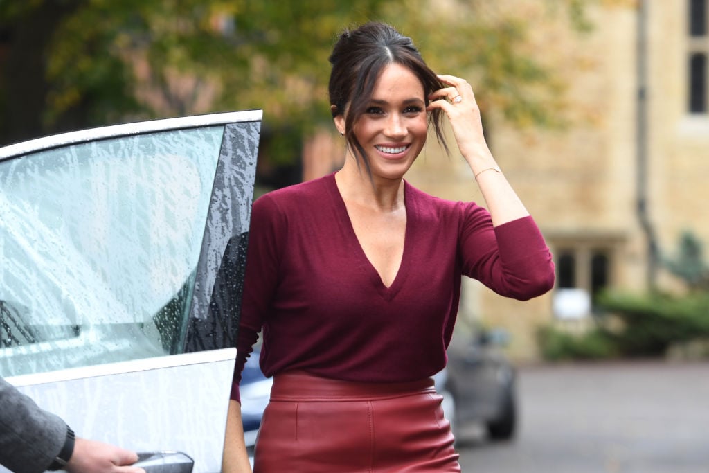 Meghan Markle smiling while stepping out of a car