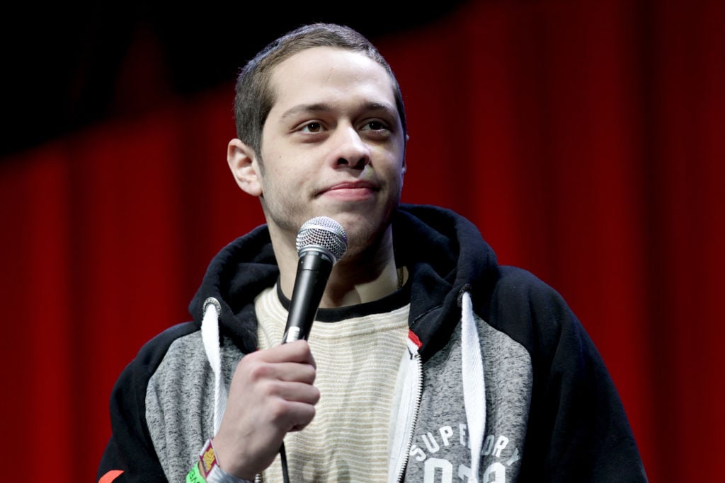 Pete Davidson on stage holding a microphone