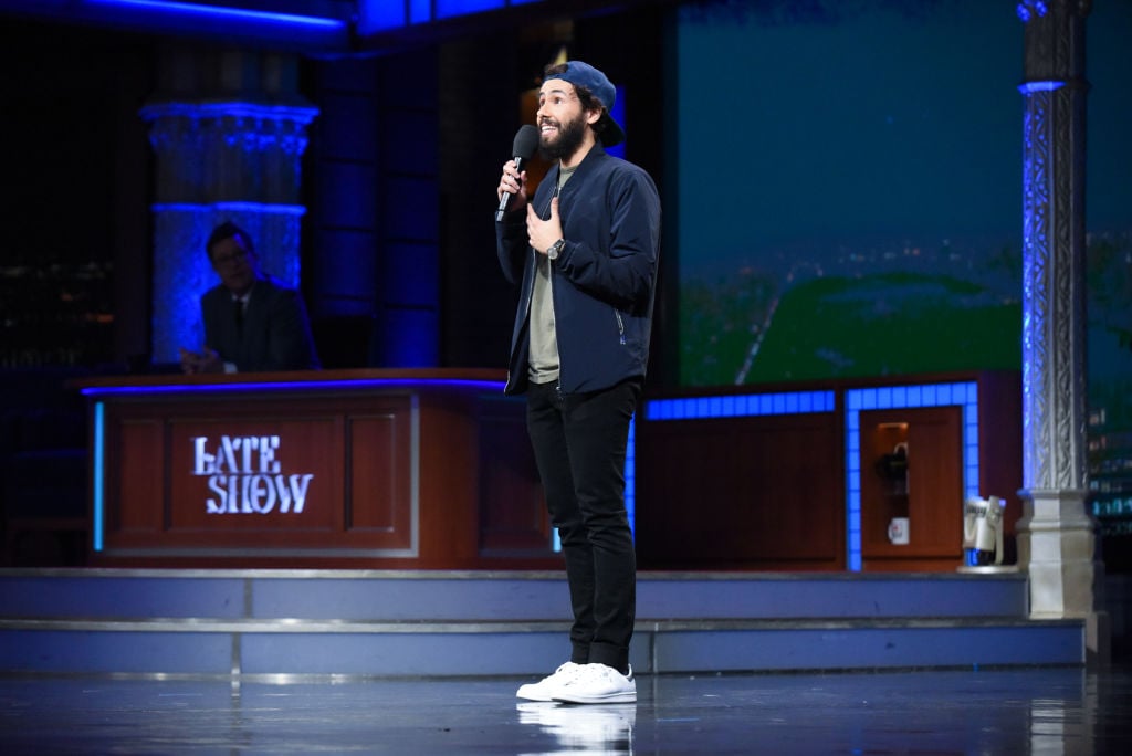 Ramy Youssef on stage holding a microphone