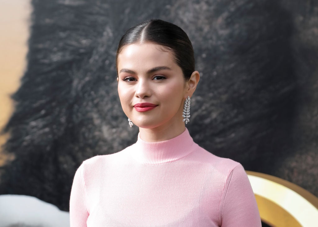 Selena Gomez smiling in front of a textured background