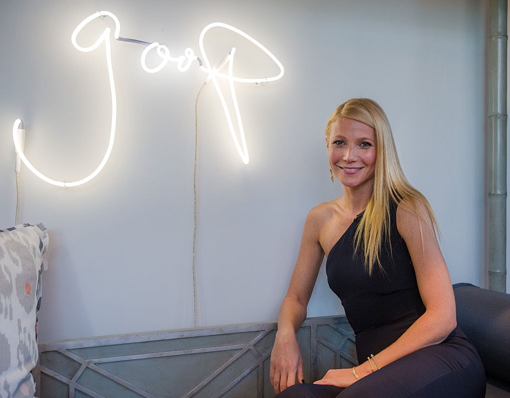 Gwyneth Paltrow posing in front of a goop sign