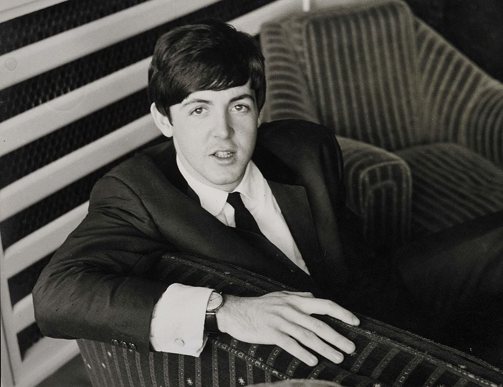 Paul McCartney sitting on a chair near a striped wall