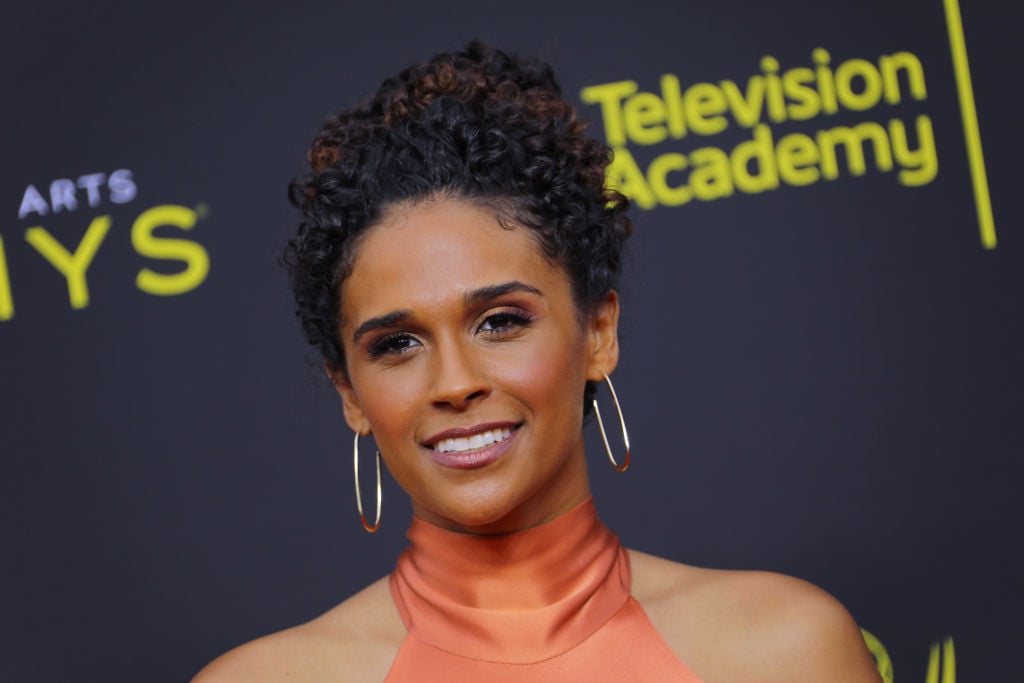 Briana Henry smiling in front of a repeating background