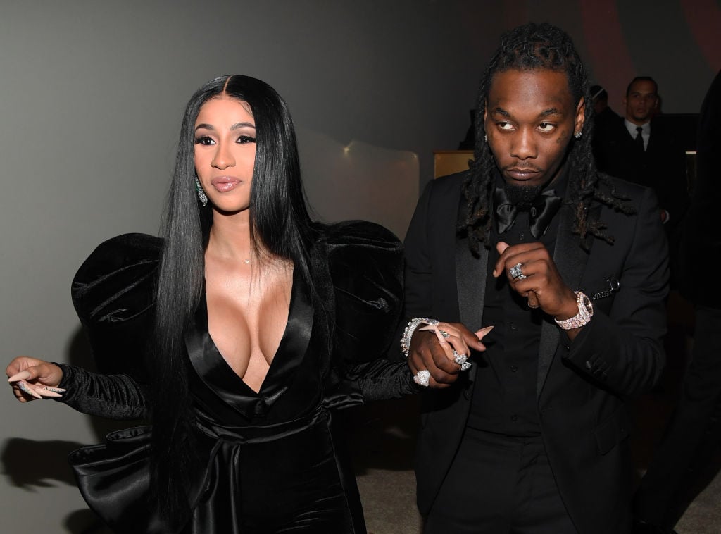 Cardi B and Offset in black outfits smiling, looking away from the camera