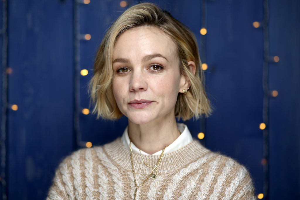 Carey Mulligan smiling in front of a dark blue wall