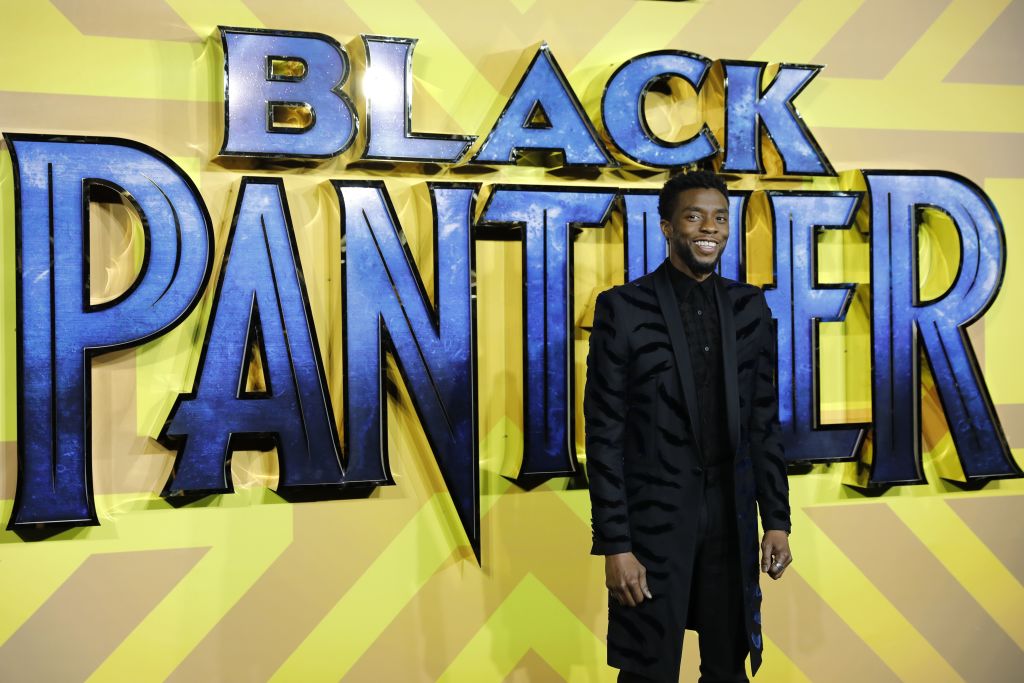 Chadwick Boseman smiling in front of the Black Panther logo