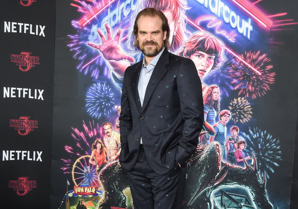 David Harbour smiling in front of a 'Stranger Things' backdrop