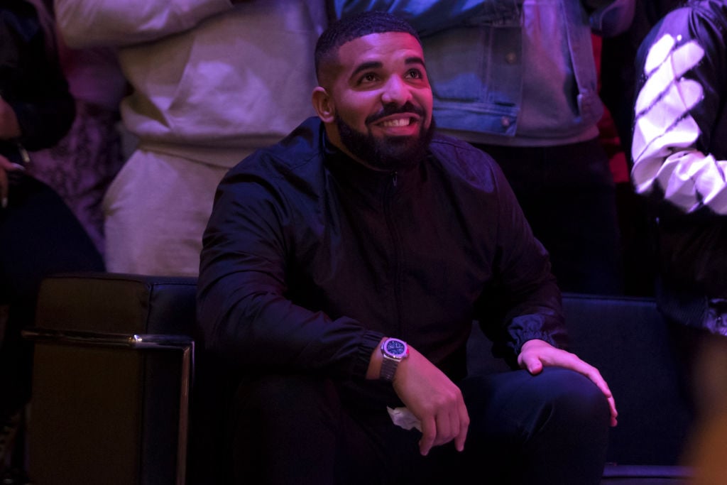 Drake smiling and looking up while seated