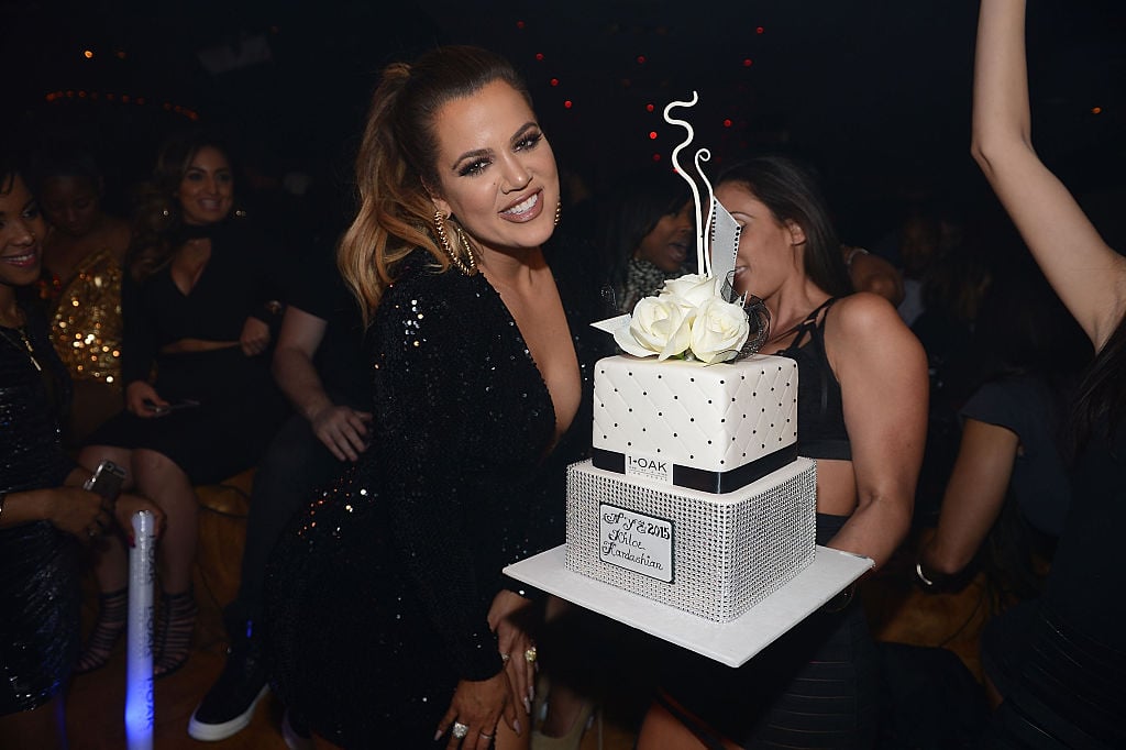 Khloé Kardashian holding a large cake in a nightclub
