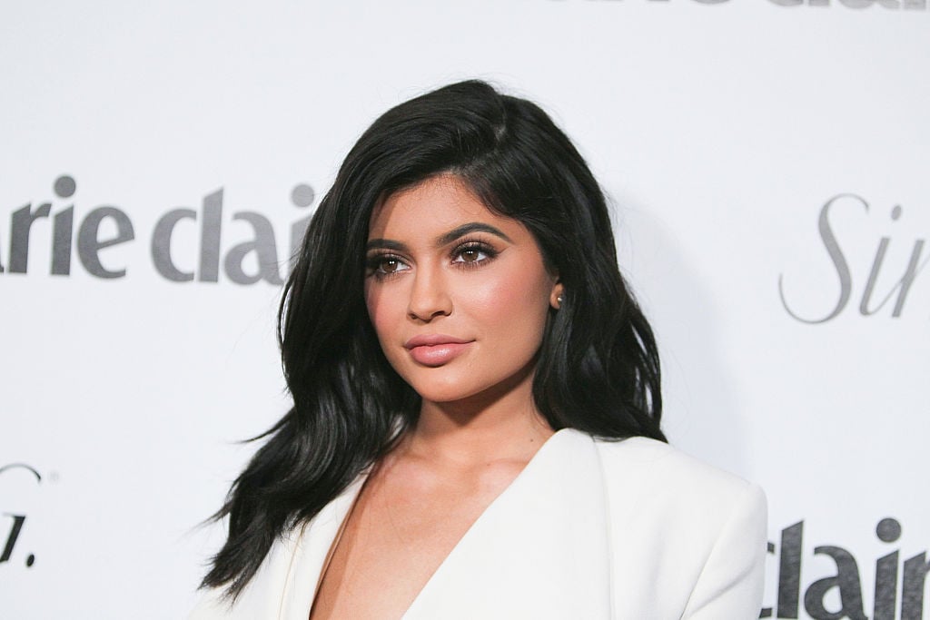 Kylie Jenner looking off camera in front of a repeating white background