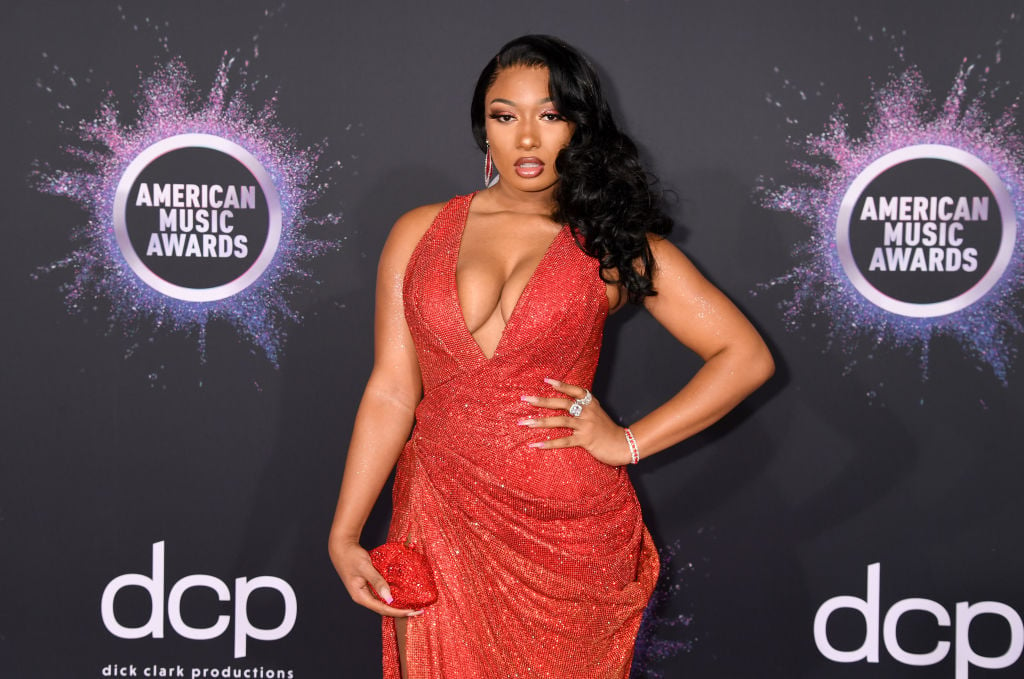 Megan Thee Stallion in a red dress in front of a repeating background