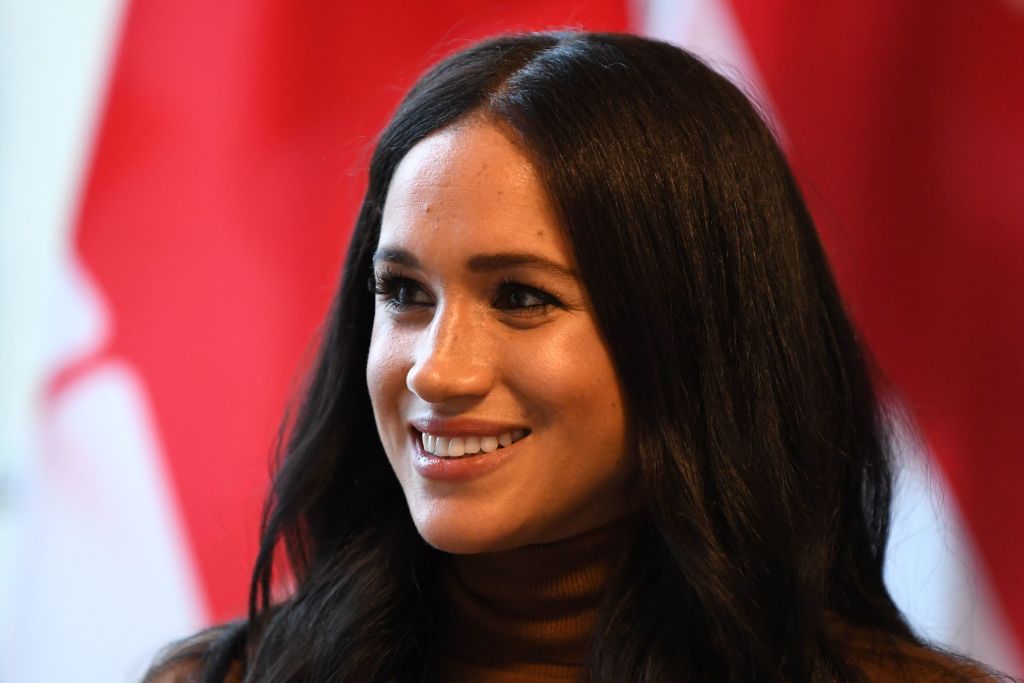 Meghan Markle close up, in front of a red and white background