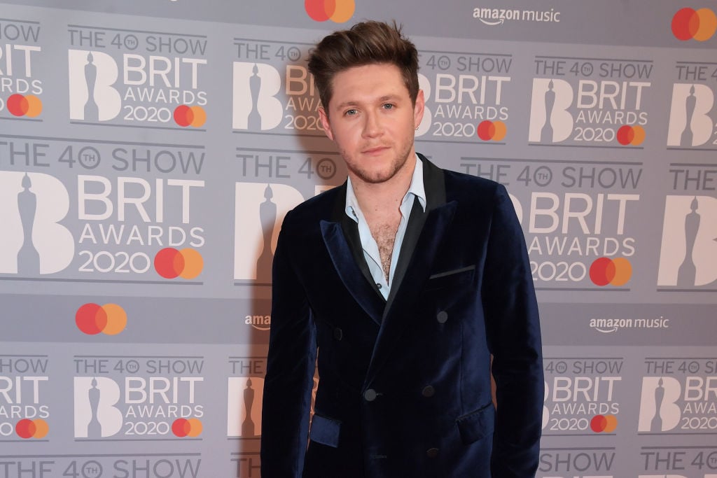 Niall Horan smiling in front of a repeating background