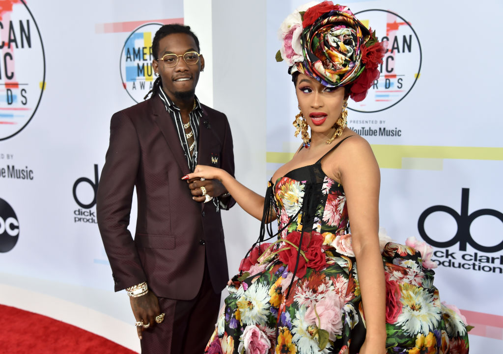Offset and Cardi B holding hands looking away from the camera