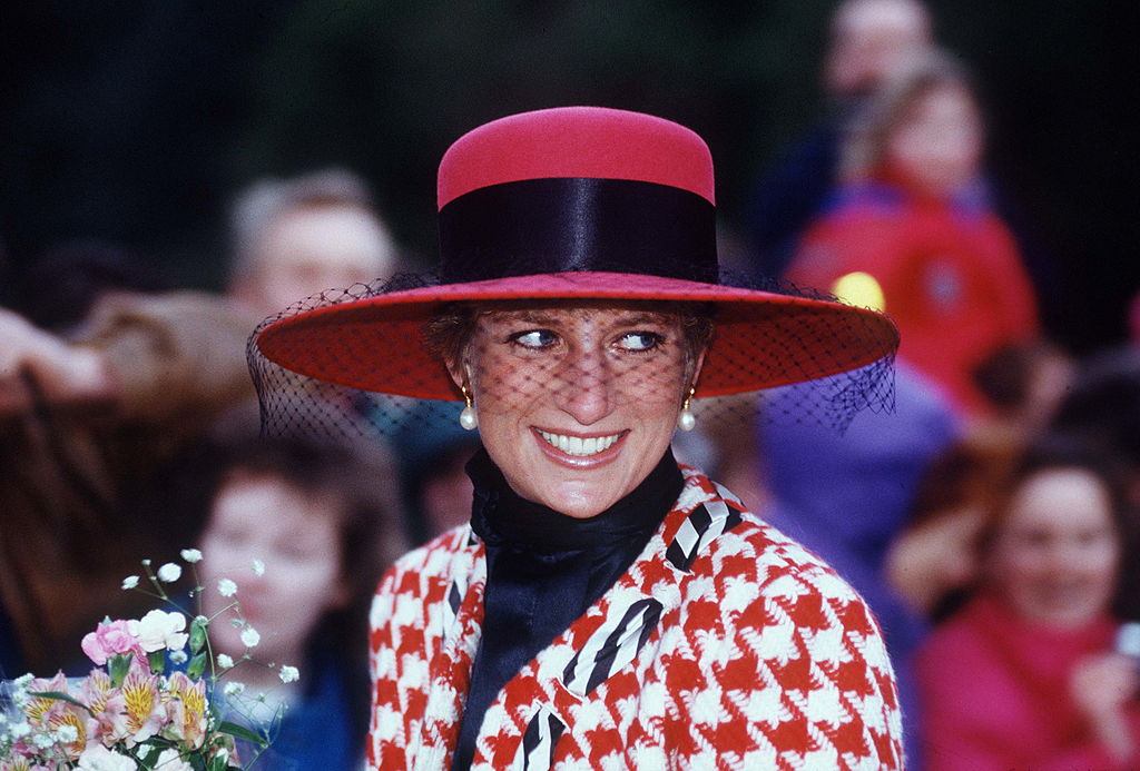 Diana, Princess Of Wales, Smiling On A Walkabout After Attending Christening Service At Sandringham Church. The Princess Is Wearing A Houndstooth Red And White Jacket Designed By Moschino With A Black Polo Neck Jumper And A Broad-brimmed Red Hat.