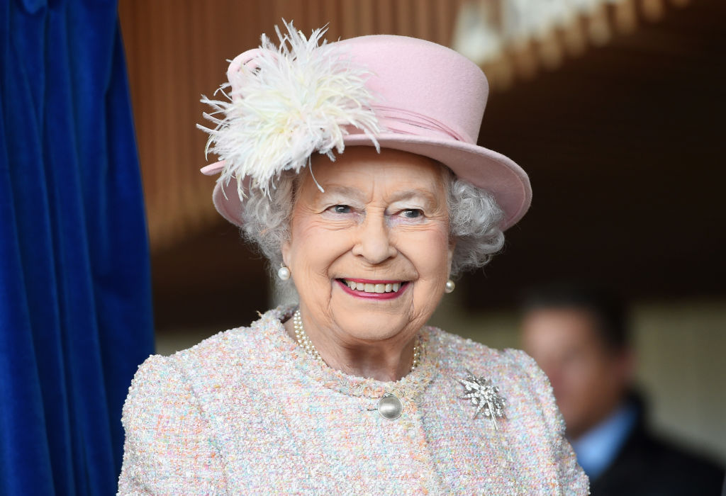 Queen Elizabeth II smiling in a pink hat